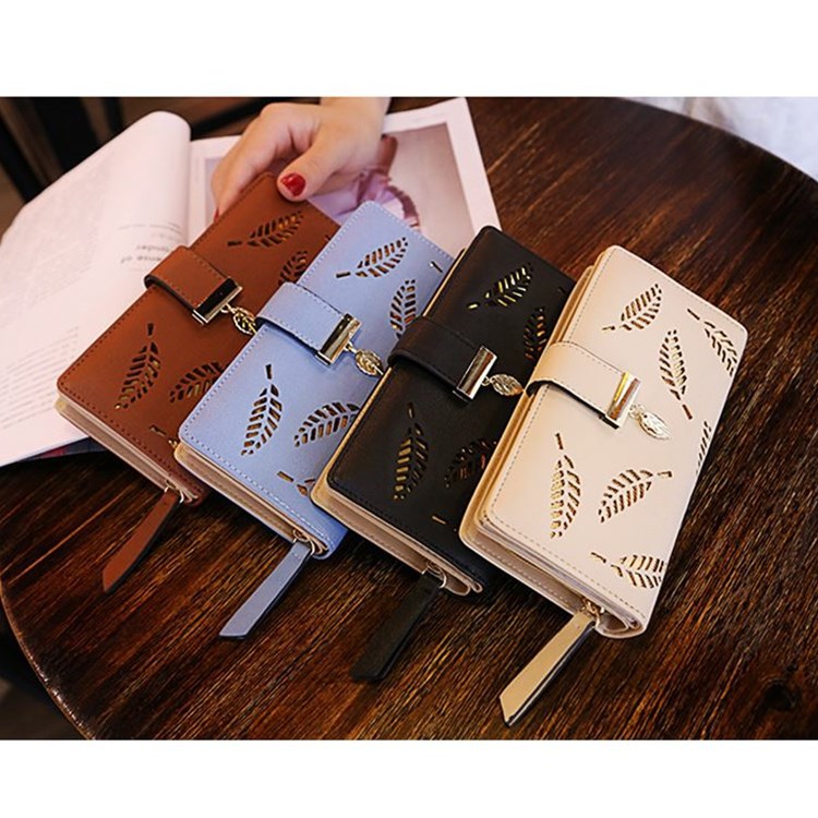 Image of model displaying four of the Gold Leaf Print Pattern Wallet in coffee, sky blue, black, and khahi and gold.