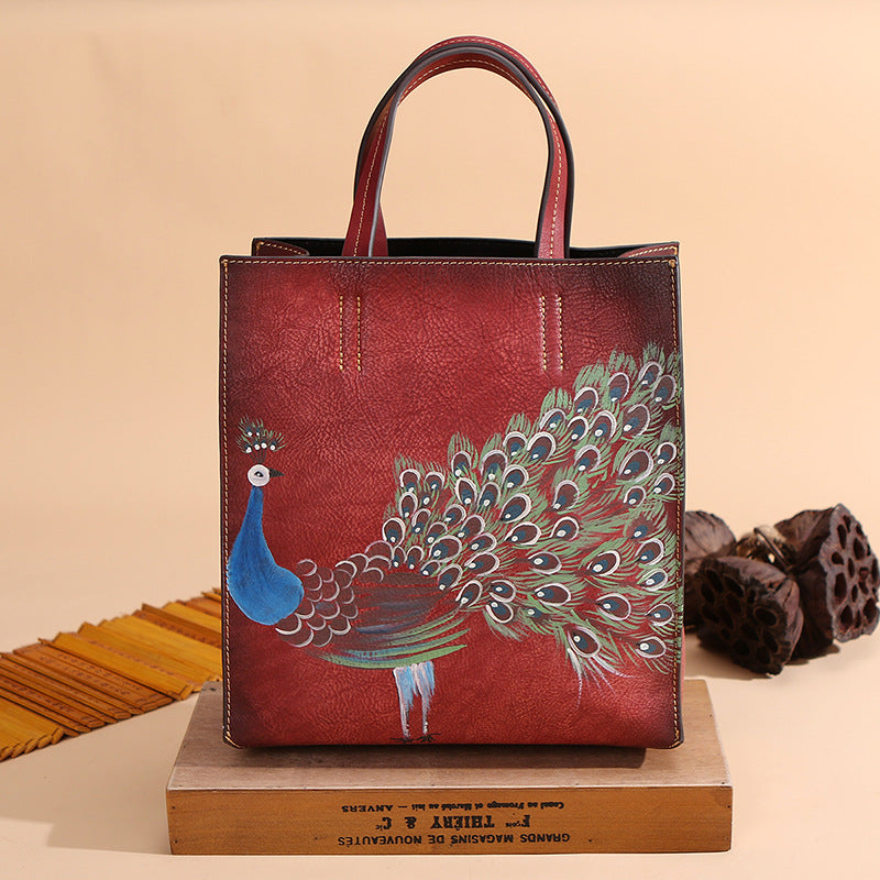 Vintage Leather Peacock Handbag positioned on top of a flat wooden box in red.