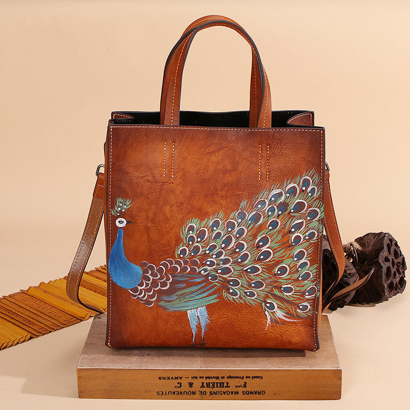Vintage Leather Peacock Handbag positioned on top of a flat wooden box in brown.