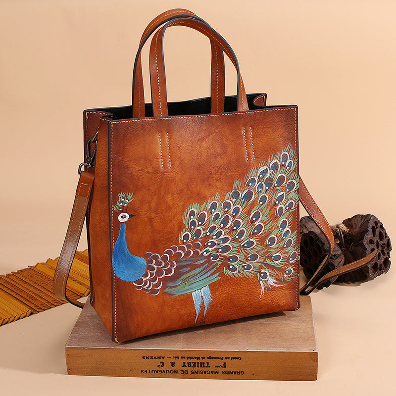 Vintage Leather Peacock Handbag positioned on top of a flat wooden box in brown.