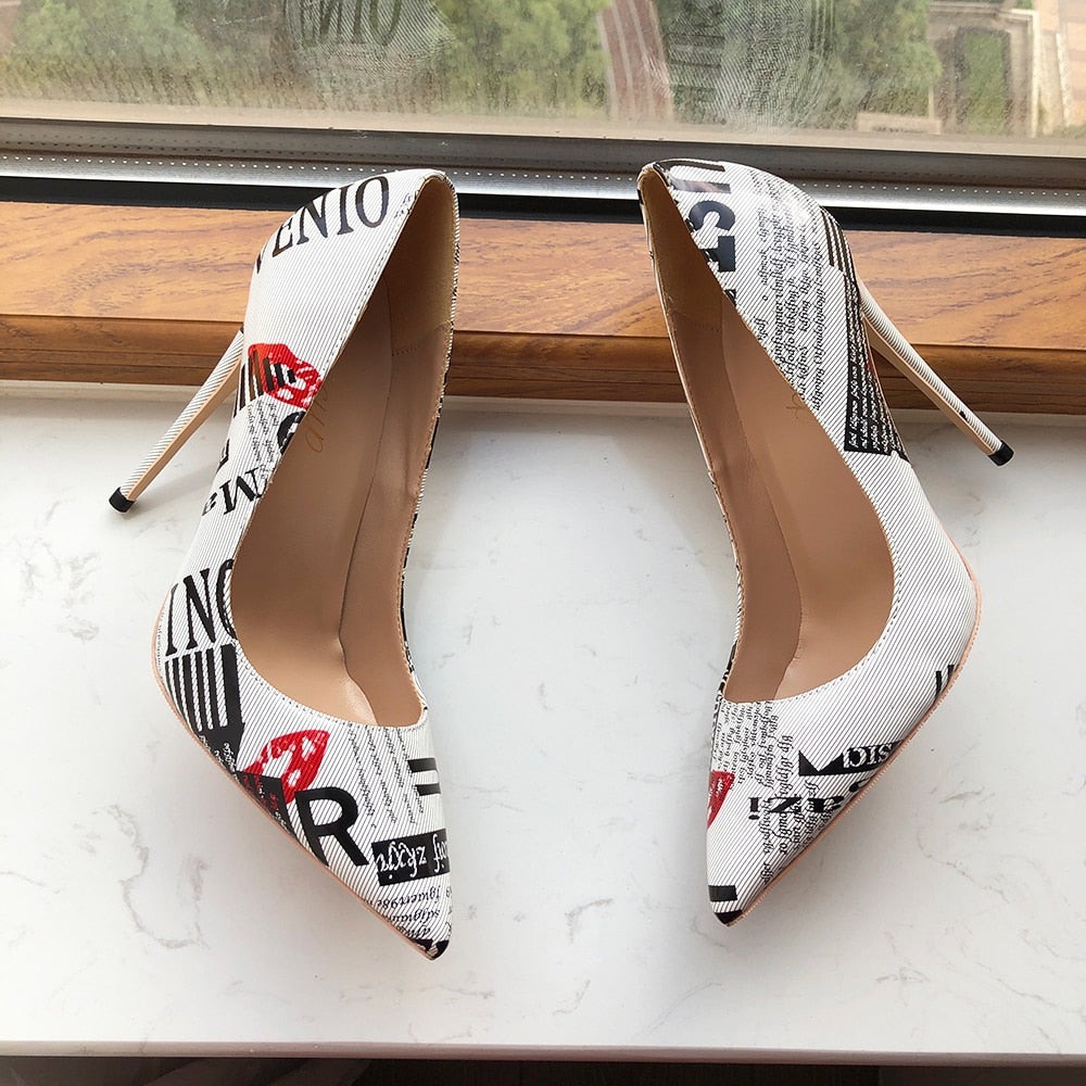 Both Designer Graphic Newspaper Print Stilettos laying on its sides by the window sill.
